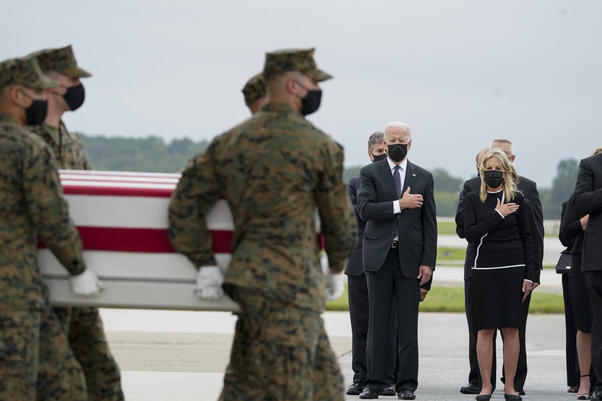 President Joe Biden and first lady Jill Biden watch as a Marine Corps carry team moves a transfer case.