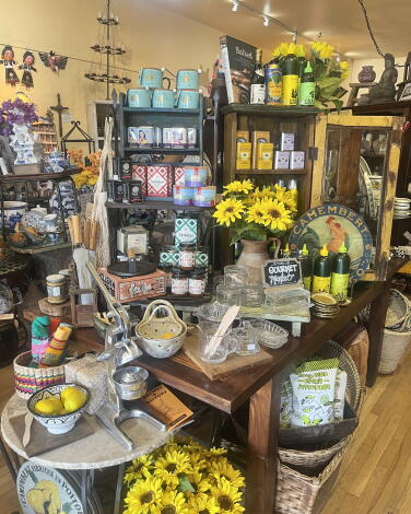 A variety of gifts on shelves and tables with bouquets of sunflowers.