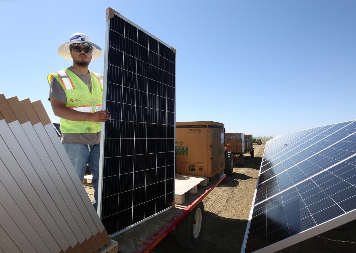 Ricky Figueroa places photovoltaic panels at the construction site of Westlands Solar Park on June 24, 2021.