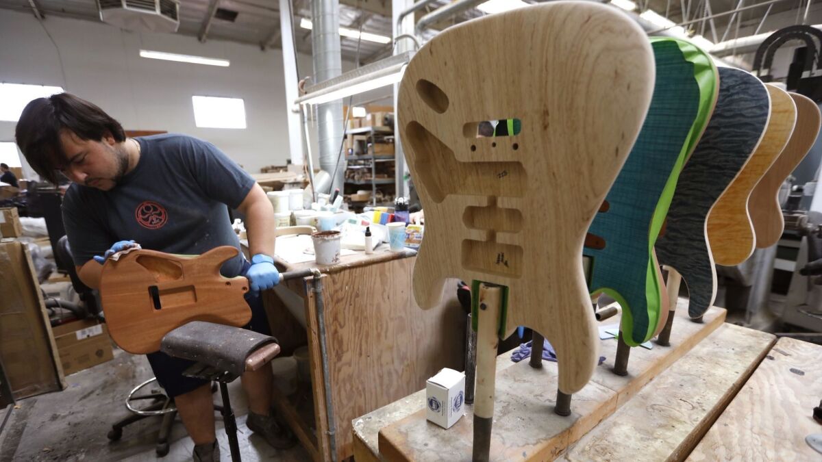 Hunter Martin, 24, a lead stainer at Guitarworks, stains a Tom Anderson Cobra guitar at the company's headquarters in Newbury Park in July.