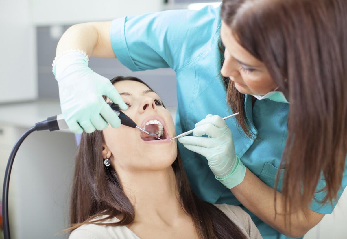 A woman receives dental care before the pandemic in a setting without masks