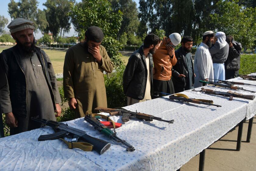 Former Afghan Taliban fighters stand next to weapons before handing them over as part of a government peace and reconciliation process at a ceremony in Jalalabad on March 1, 2020. - The United States signed a landmark deal with the Taliban on February 29, laying out a timetable for a full troop withdrawal from Afghanistan within 14 months as it seeks an exit from its longest war. (Photo by NOORULLAH SHIRZADA / AFP) (Photo by NOORULLAH SHIRZADA/AFP via Getty Images)