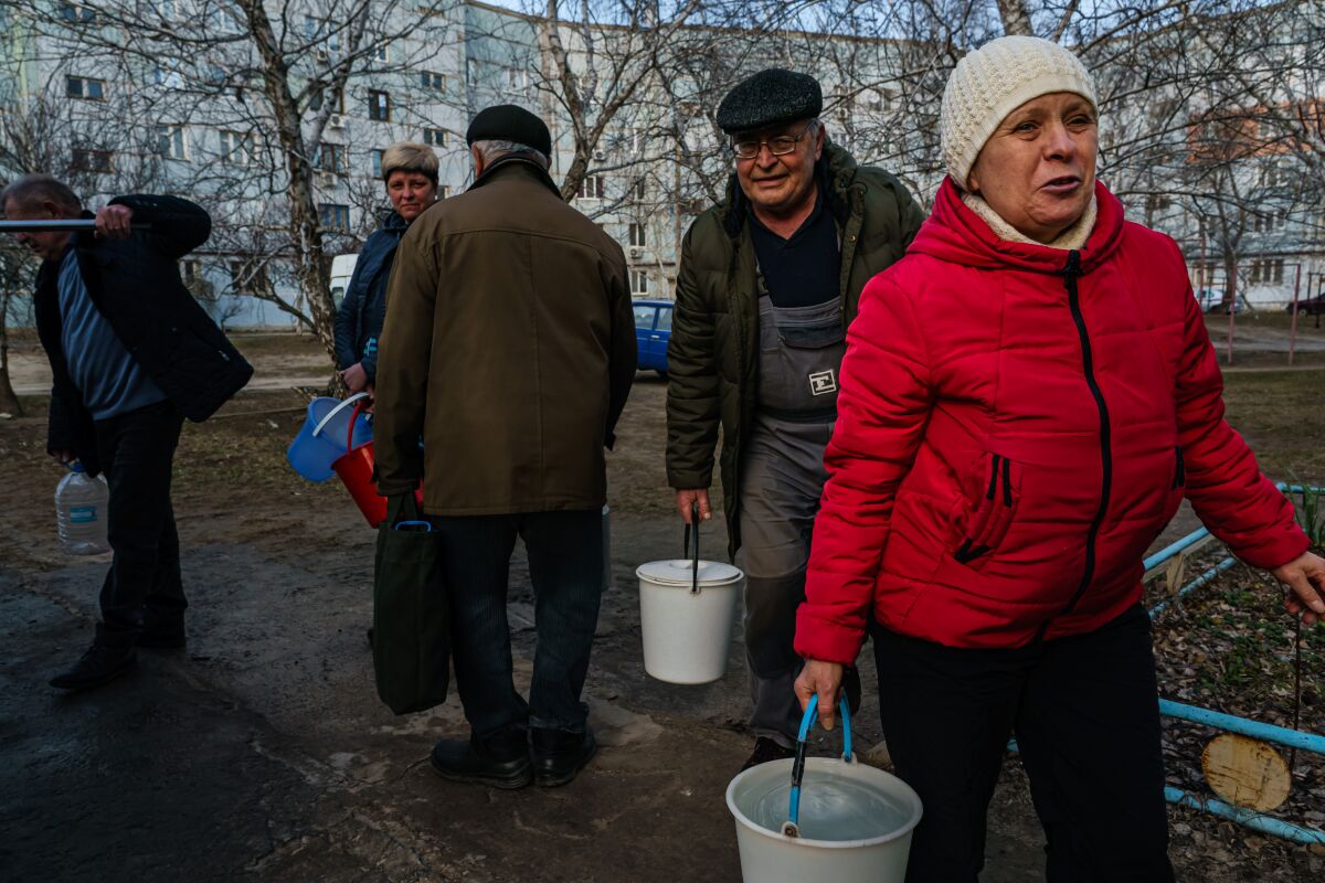 People fill buckets with water outdoors