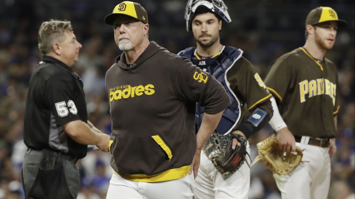 San Diego Padres bench coach Mark McGwire, front, walks back to the dugout after making a pitching change during the fourth inning of the team's baseball game against the Los Angeles Dodgers on Friday, June 30, 2017, in San Diego.