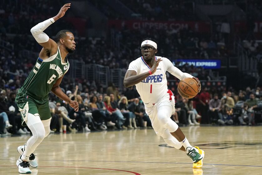 Los Angeles Clippers guard Reggie Jackson, right, drives by Milwaukee Bucks guard Rodney Hood during the first half of an NBA basketball game Sunday, Feb. 6, 2022, in Los Angeles. (AP Photo/Mark J. Terrill)
