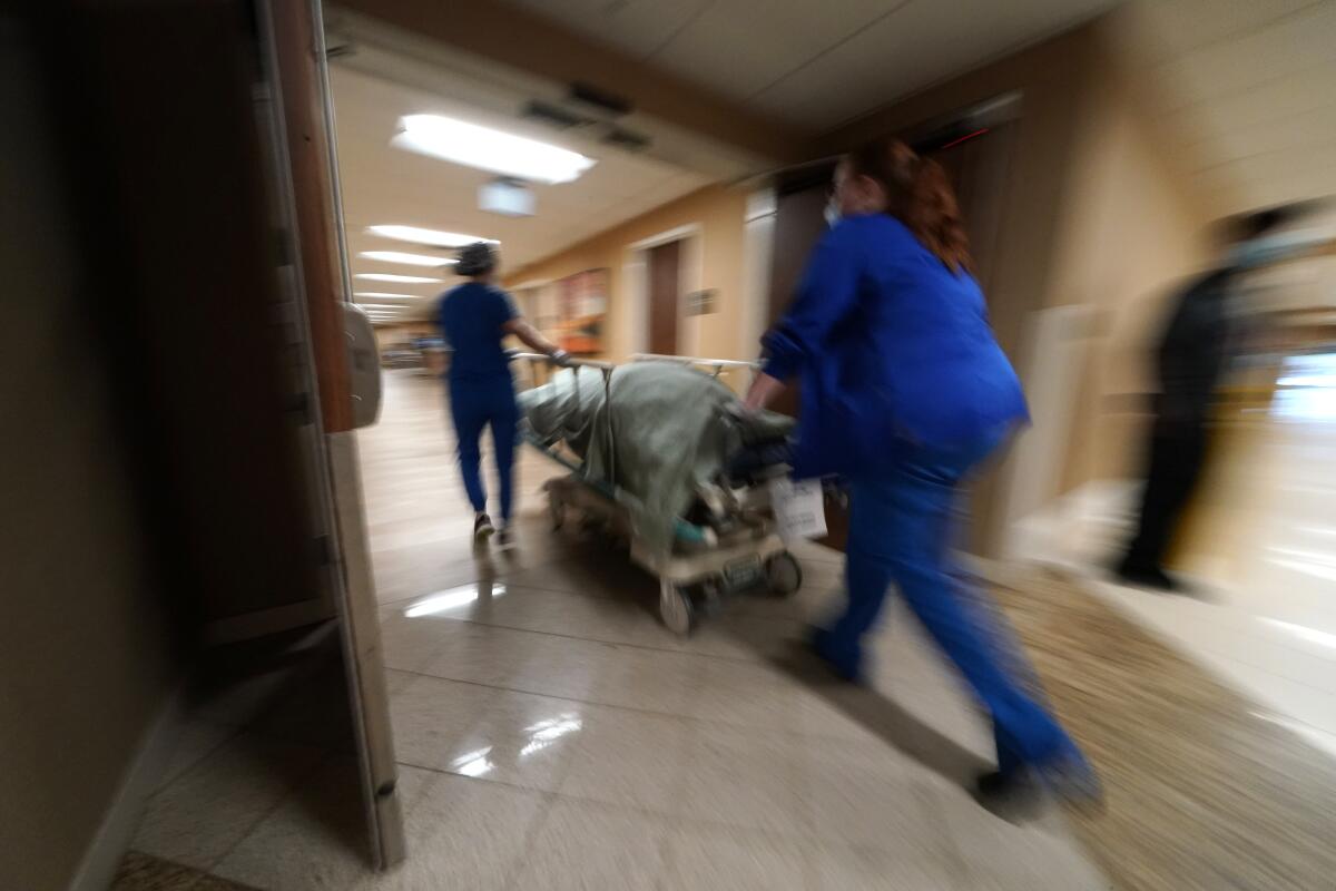 Medical personnel wheeling a patient on a gurney through hospital doors