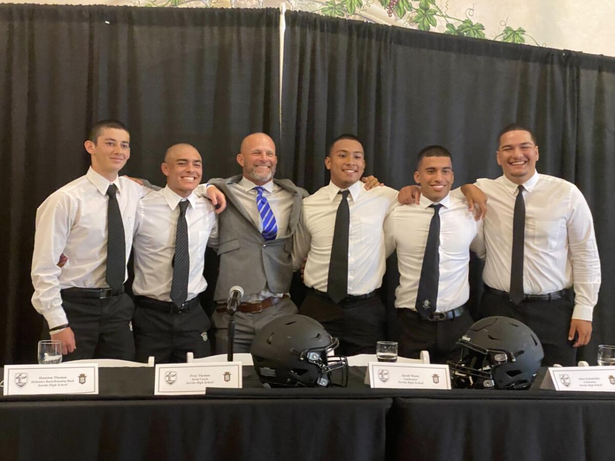 Servite players surround coach Troy Thomas for a photo at Trinity League media day.