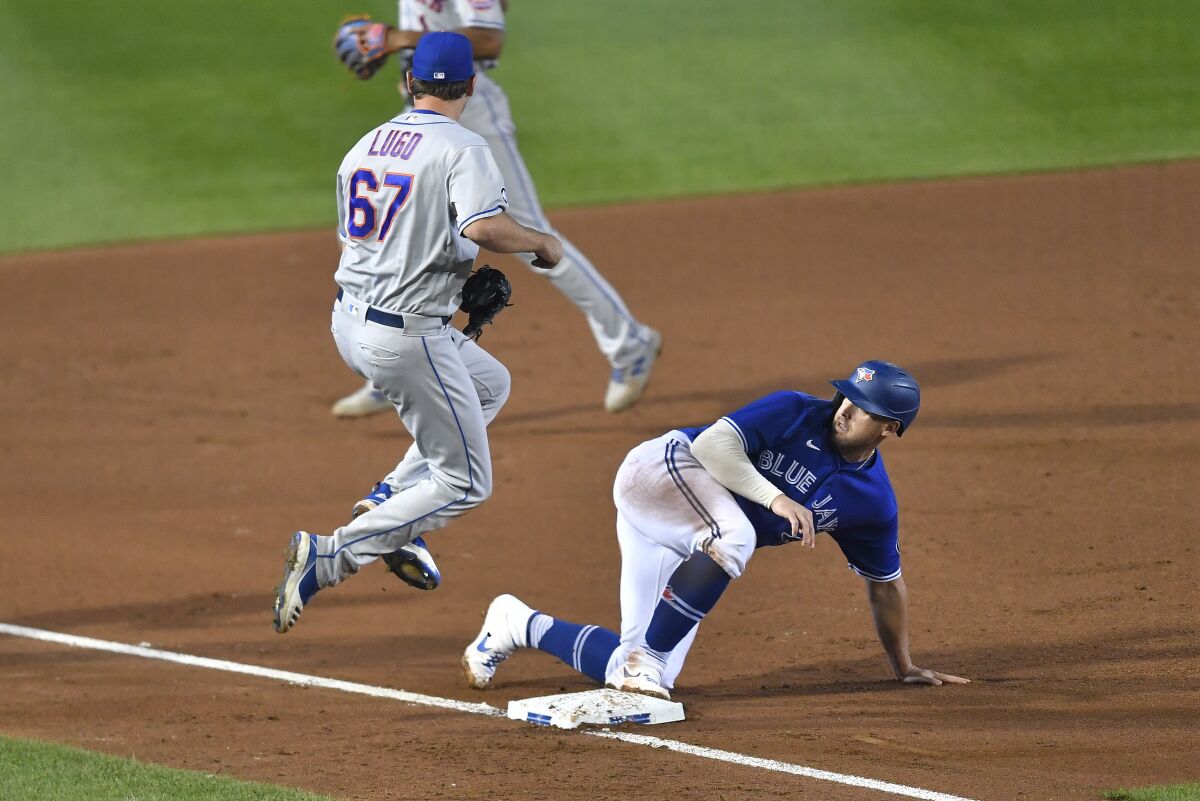 New York Mets starting pitcher Seth Lugo, left, jumps off the base after forcing out Toronto Blue Jays' Travis Shaw at third during the fourth inning of a baseball game in Buffalo, N.Y., Saturday, Sept. 12, 2020. The call was upheld after a Toronto challenge. (AP Photo/Adrian Kraus)