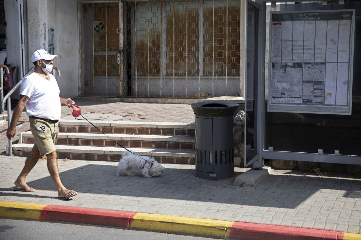 An Israeli man walks a dog near a trashcan installed next to a bus stop that applauds to those who use it, in Jerusalem, Thursday, Oct. 14, 2021. Drop a piece of trash in, and a recording of a child's voice says "Thank you very much!". (AP Photo/Sebastian Scheiner)