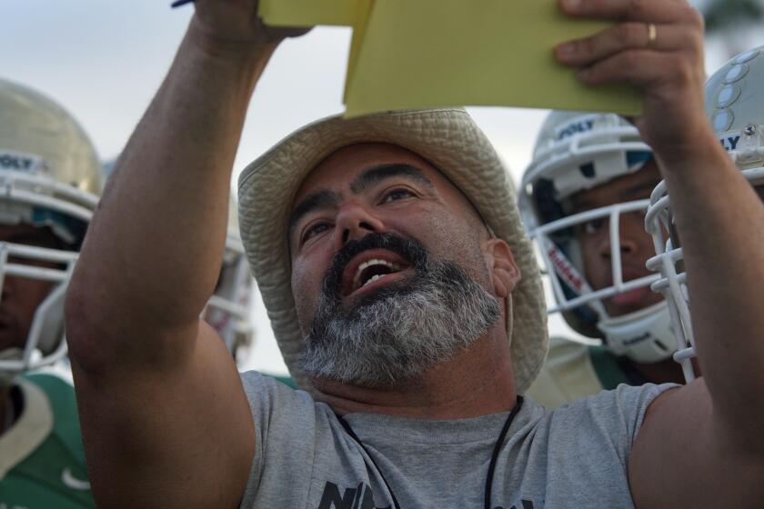 LONG BEACH, CA September 25, 2013 -- Football coach Raul Lara shows his team a play to run during practice at Long Beach Poly on September 25 2013. (Cheryl A. Guerrero / Los Angeles Times)