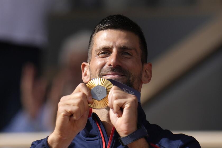 El serbio Novak Djokovic muestra su medalla de oro tras vencer a Carlos Alcaraz en la final de sencillos masculino del tenis de los Juegos Olímpicos de París, el domingo 4 de agosto de 2024. (AP Foto/Manu Fernández)
