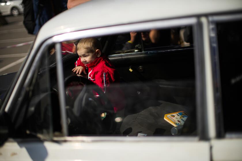 A child looks through a car windshield as his family waits to be processed upon their arrival from Vasylivka at a reception center for displaced people in Zaporizhzhia, Ukraine, Monday, May 2, 2022. Thousands of Ukrainian continue to leave Russian occupied areas. (AP Photo/Francisco Seco)