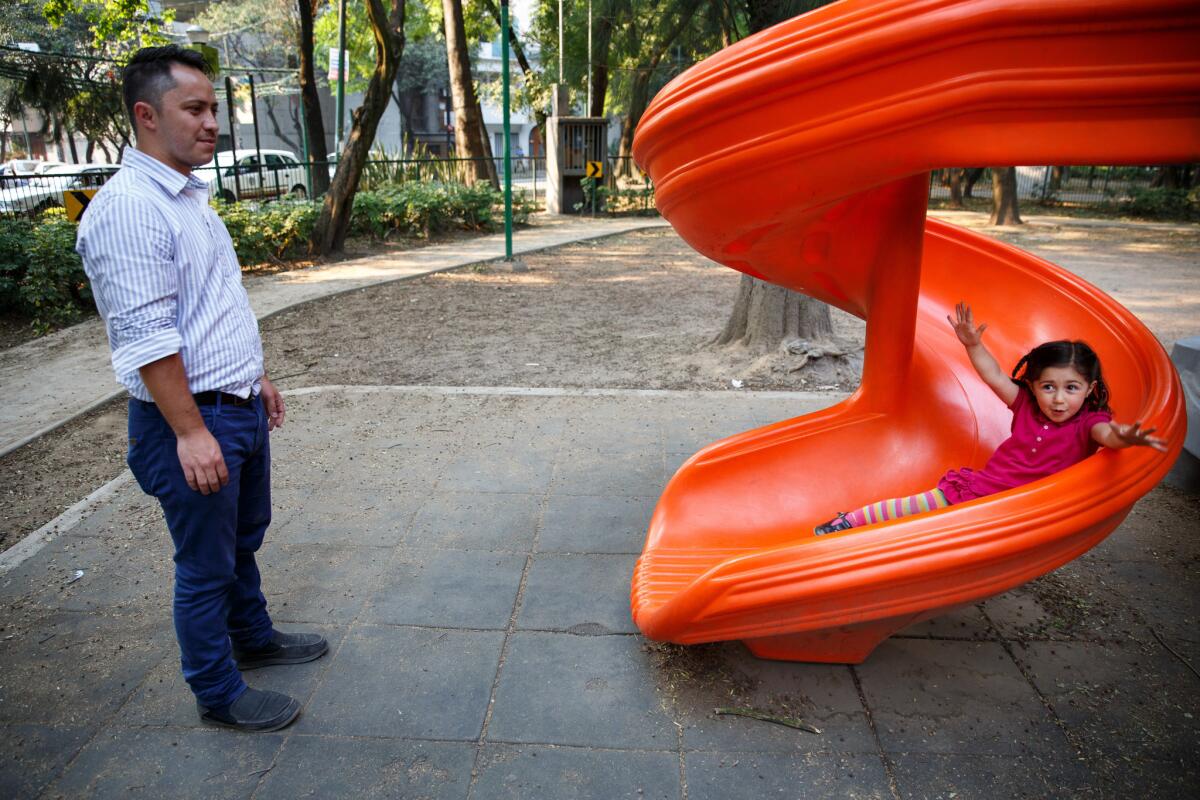 Carlos Esquerre watches his daughter, Helena, 3, play on a slide in Mexico City's Parque Espana.