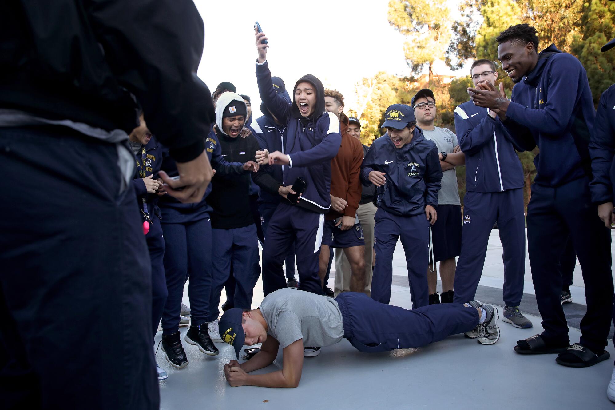 A person lies on the ground as standing people around them clap.