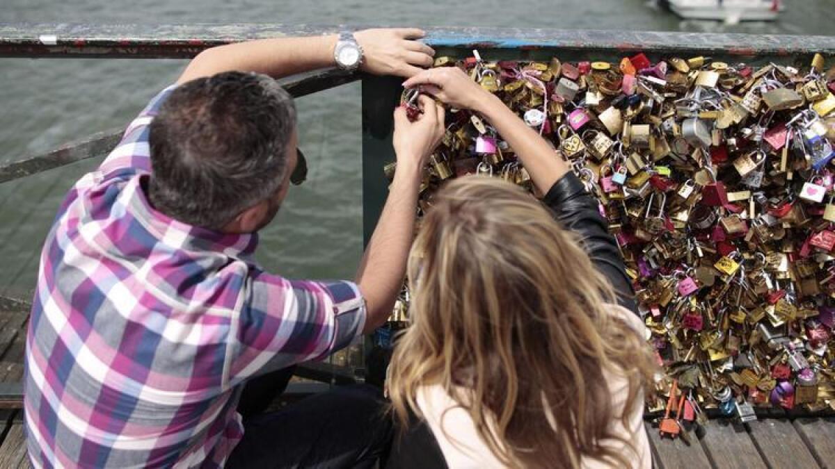 Una pareja coloca un candado sobre el histórico Puente de las Artes en París. El año pasado, una sección de cinco pies de la barandilla del puente se derrumbó.