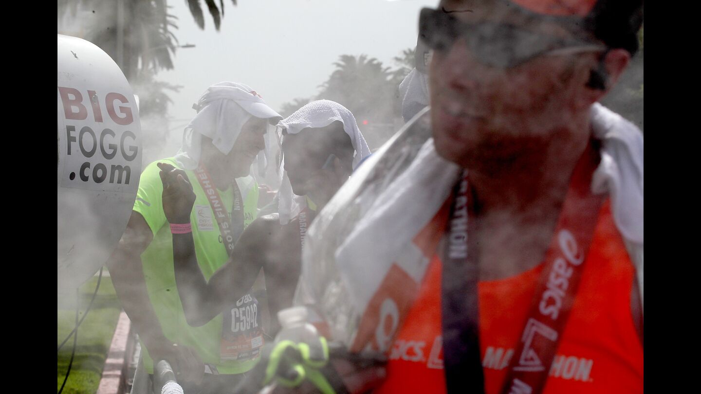 Runners cool off in misters after crossing the finish line of the 30th Los Angeles Marathon in Santa Monica.