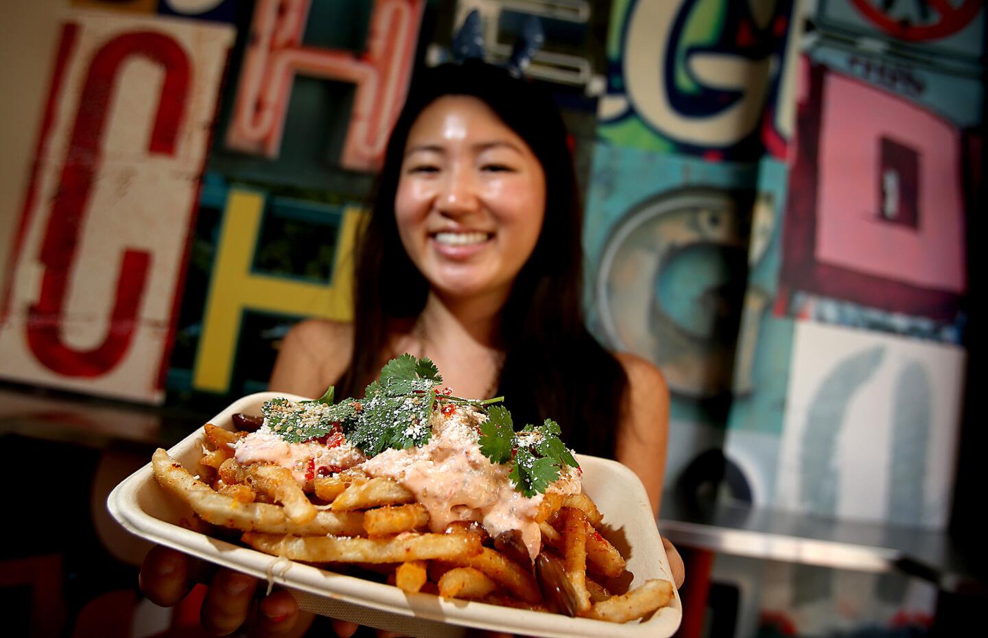 Alice Shin shows off Chego's Ooey Gooey Fries, made of beer-battered potatoes topped with sour cream sambal, Monterey Jack and cheddar cheese, cotija, chiles, cilantro and pickled garlic.