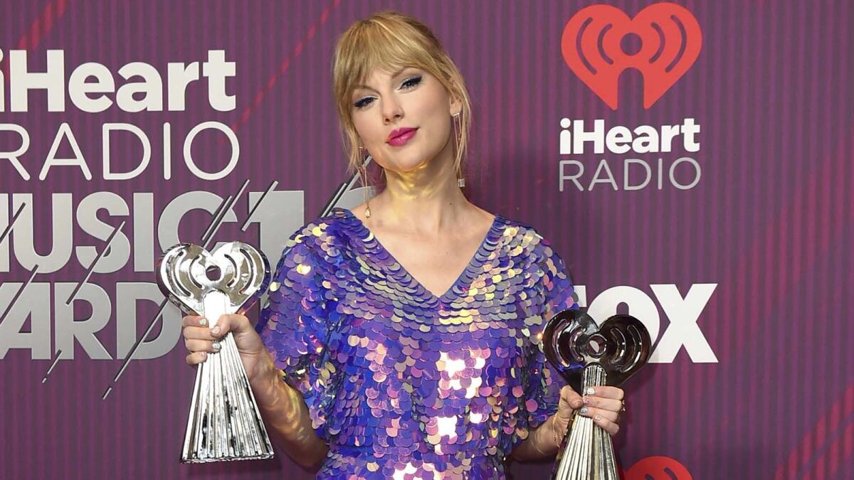 Taylor Swift poses with her iHeartRadio Awards in the press room at L.A.’s Microsoft Theater in March.