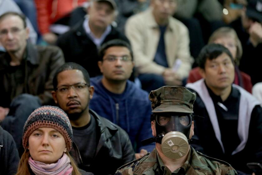 Brian Seligman, a former Marine, wears a gas mask as he joins hundreds of people gathered in the gym of Granada Hills Charter High School to participate in a meeting of the South Coast Air Quality Management District last week.