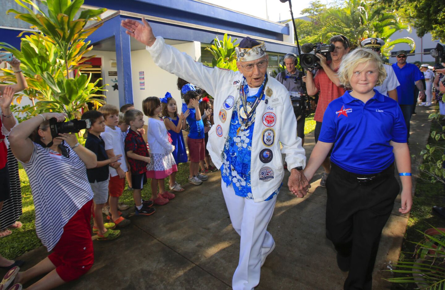 USS West Virginia, 95-year-old Pearl Harbor survivor Stu Hedley acknowledges the students at Navy Hale Keiki School as he arrives at the school escorted by fourth grader Liam Boland. He and about 24 other World War II veterans, sponsored by the Greatest Generations Foundation, of which about 15 are Pearl Harbor survivors, visited with the students, and as Hedley did, some told their stories of survival on December 7, 1941, the day Japan attacked Pearl Harbor thrusting The United States into World War II.