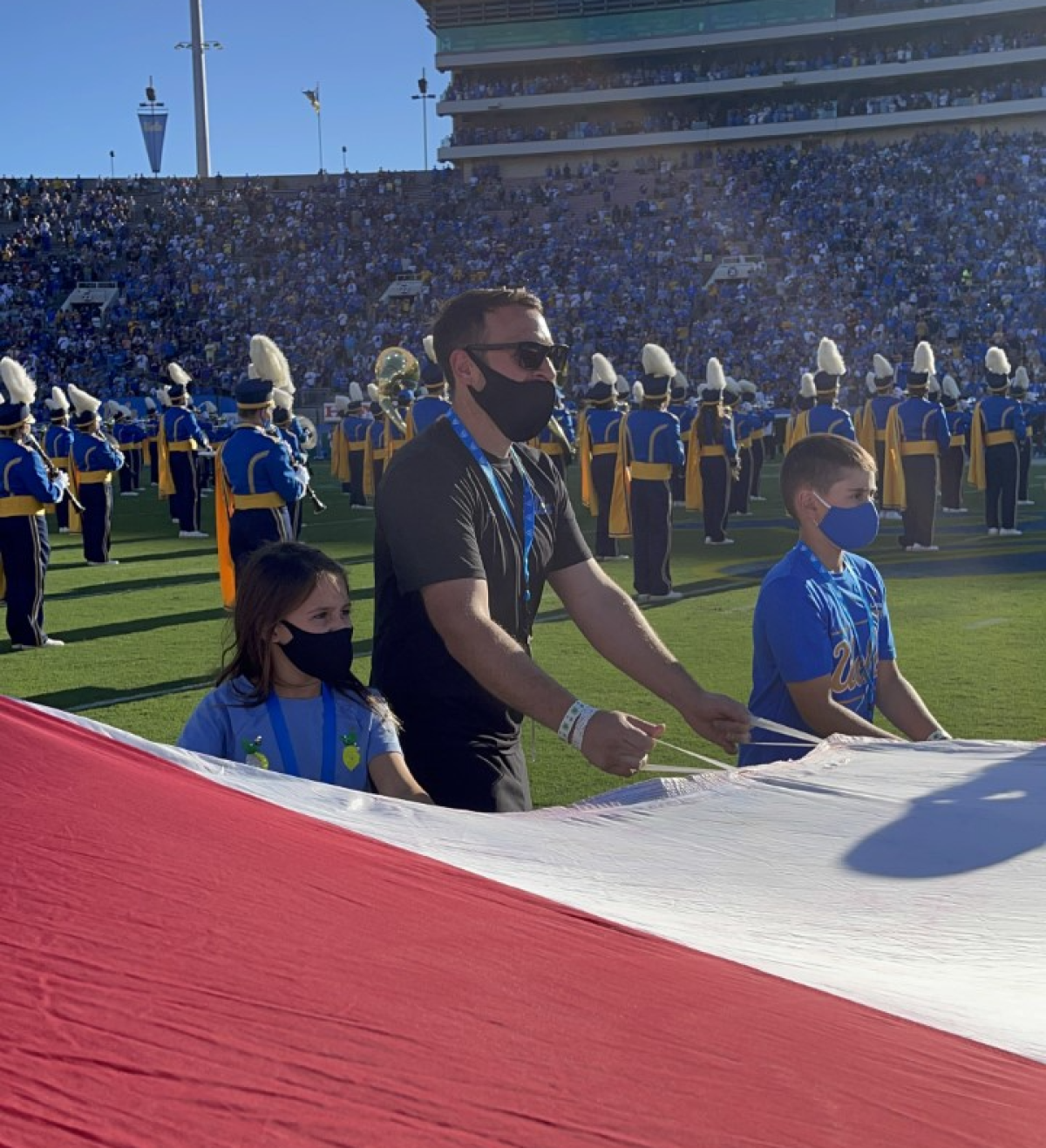 David Witzling, center, holds an American flag on the field at the Rose Bowl with his children.