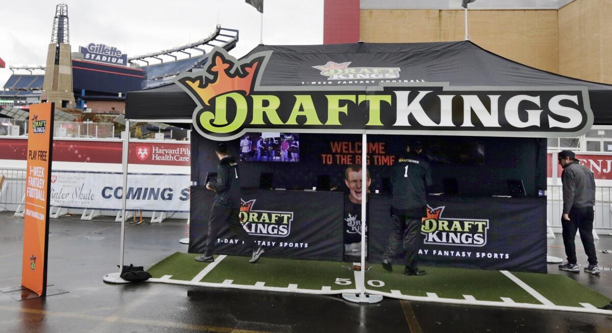 Workers set up a DraftKings promotions tent in the parking lot of Gillette Stadium, in Foxborough, Mass., before an NFL football game in this file photo. New York's attorney general on Tuesday ordered the daily fantasy sports companies DraftKings and FanDuel to stop accepting bets in the state, saying their operations amount to illegal gambling.