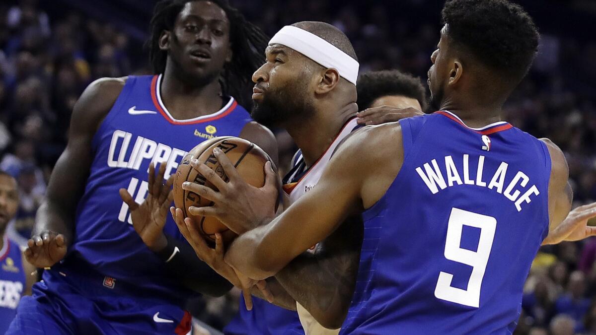 Warriors center DeMarcus Cousins tries to power his way past the Clippers' Johnathan Motley, left, and Tyrone Wallace (9) during the second half Sunday.