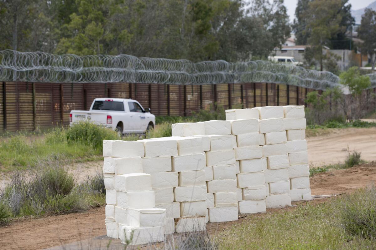 Concertina wire tops the border wall behind Cavallaro’s blocks of cheese.