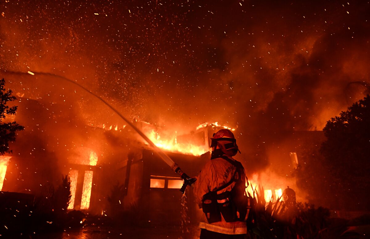 A firefighter sprays water onto a burning house