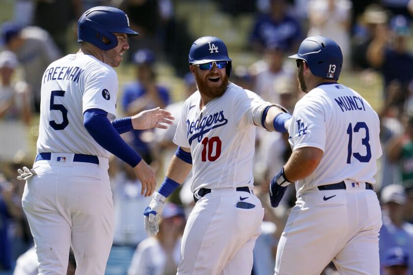 Los Angeles Dodgers' Justin Turner, center, celebrates his three-run home run at home plate with Max Muncy (13) and Freddie Freeman (5) during the fifth inning of a baseball game against the San Francisco Giants Wednesday, Sept. 7, 2022, in Los Angeles. (AP Photo/Marcio Jose Sanchez)