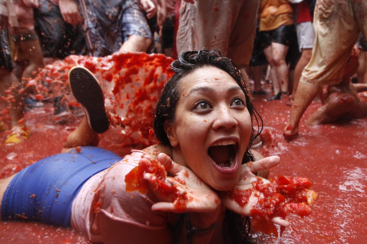 A participant in La Tomatina lies in a pool of tomatoes.