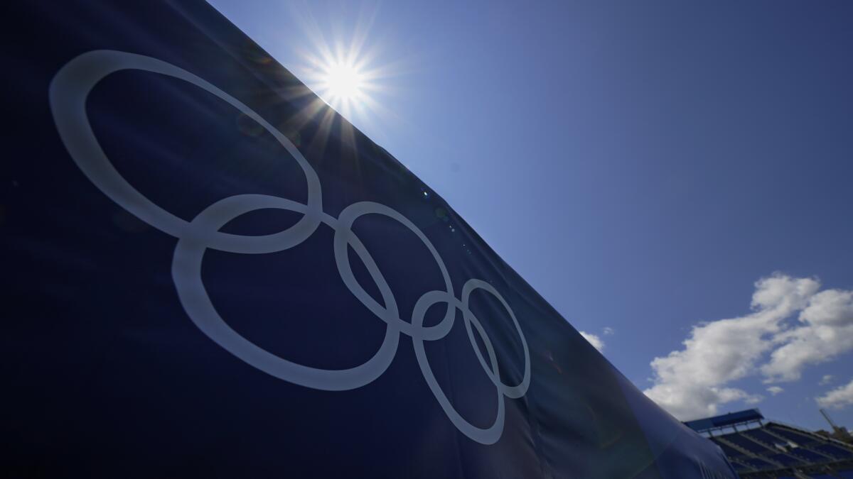 The sun shines behind Olympic rings at a stadium during the Tokyo Olympics.