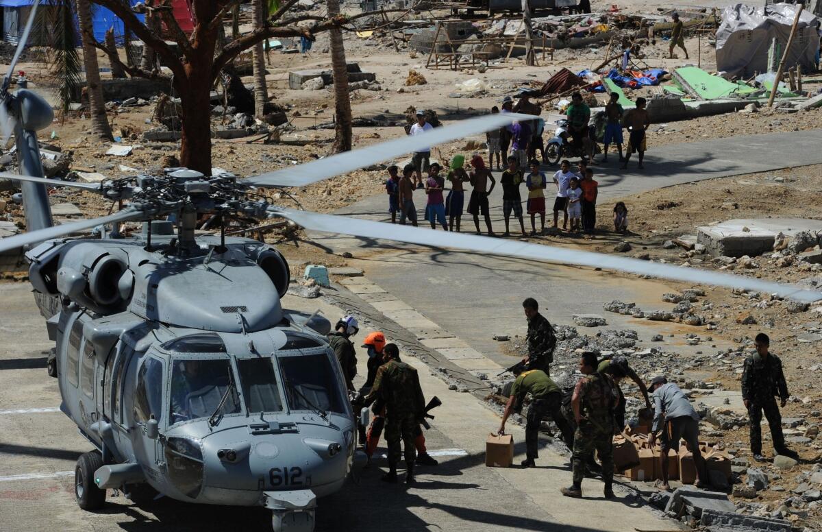 U.S. and Philippine military personnel unload relief food from a U.S. Navy Seahawk helicopter in the town of Hernani, Eastern Samar province, on Monday. The Obama administration reported Tuesday that 9,500 U.S. military personnel have been dispatched to the Philippines to help in the aftermath of Typhoon Haiyan.