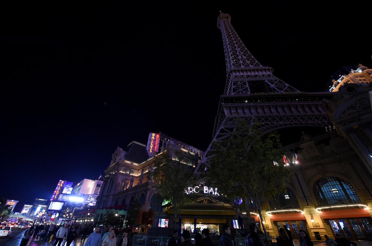 Tourists walk on the Las Vegas Strip in front of the Paris Las Vegas' 50-story Eiffel Tower replica which was dimmed in a show of solidarity with France on November 14, 2015 in Las Vegas, Nevada.