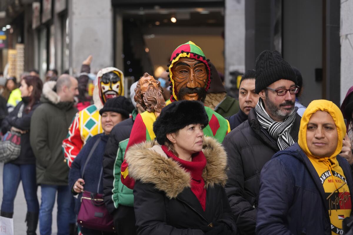 Dos personas con máscaras hacen fila para comprar lotería de Navidad en el centro de Madrid, España, 