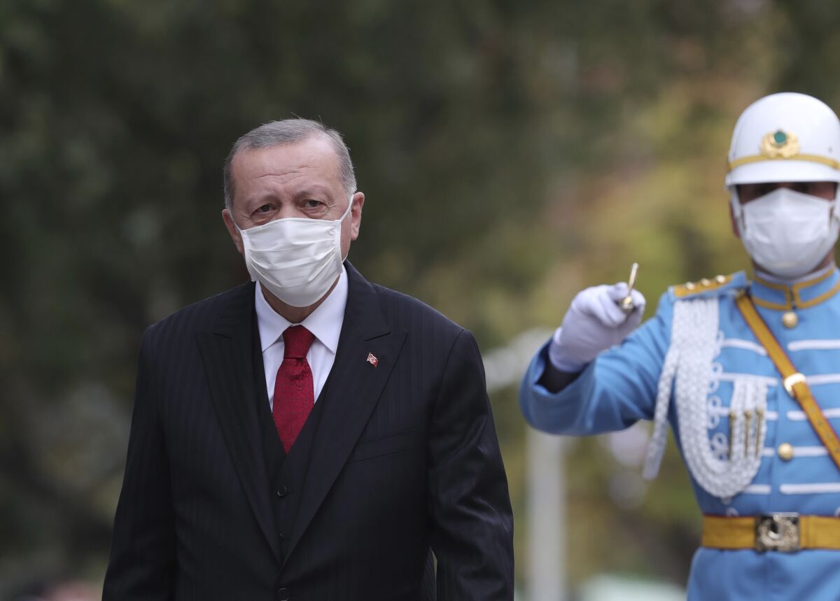 Turkey's President Recep Tayyip Erdogan, wearing a face mask to help prevent the spread of the coronavirus, inspects a military honour guard at the parliament, in Ankara, Turkey, Thursday, Oct. 1, 2020. Turkey's government is being accused of hiding the true extent of the country's coronavirus outbreak after the health minister revealed that the daily COVID-19 figures published by his ministry reflect only patients with symptoms and not all positive cases. (Turkish Presidency via AP. Pool)
