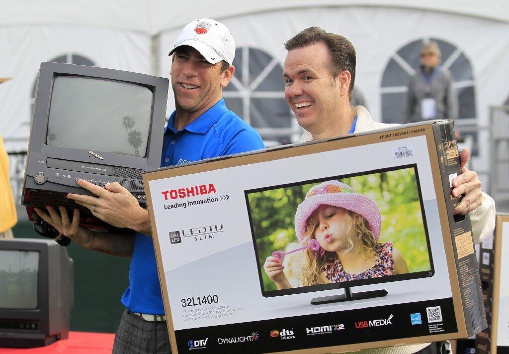 Team UCLA's John Ireland, right, and Team USC's Mark Williard, both sportscasters, show off their prizes after UCLA won the second annual Toshiba Classic Skills Challenge at Newport Beach Country Club on Tuesday.