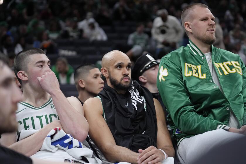 Boston Celtics guard Payton Pritchard, left, guard Derrick White, center, and center Kristaps Porzingis, right, watch from the bench as the Cleveland Cavaliers lead the Celtics during the second half of Game 2 of an NBA basketball second-round playoff series, Thursday, May 9, 2024, in Boston. (AP Photo/Steven Senne)