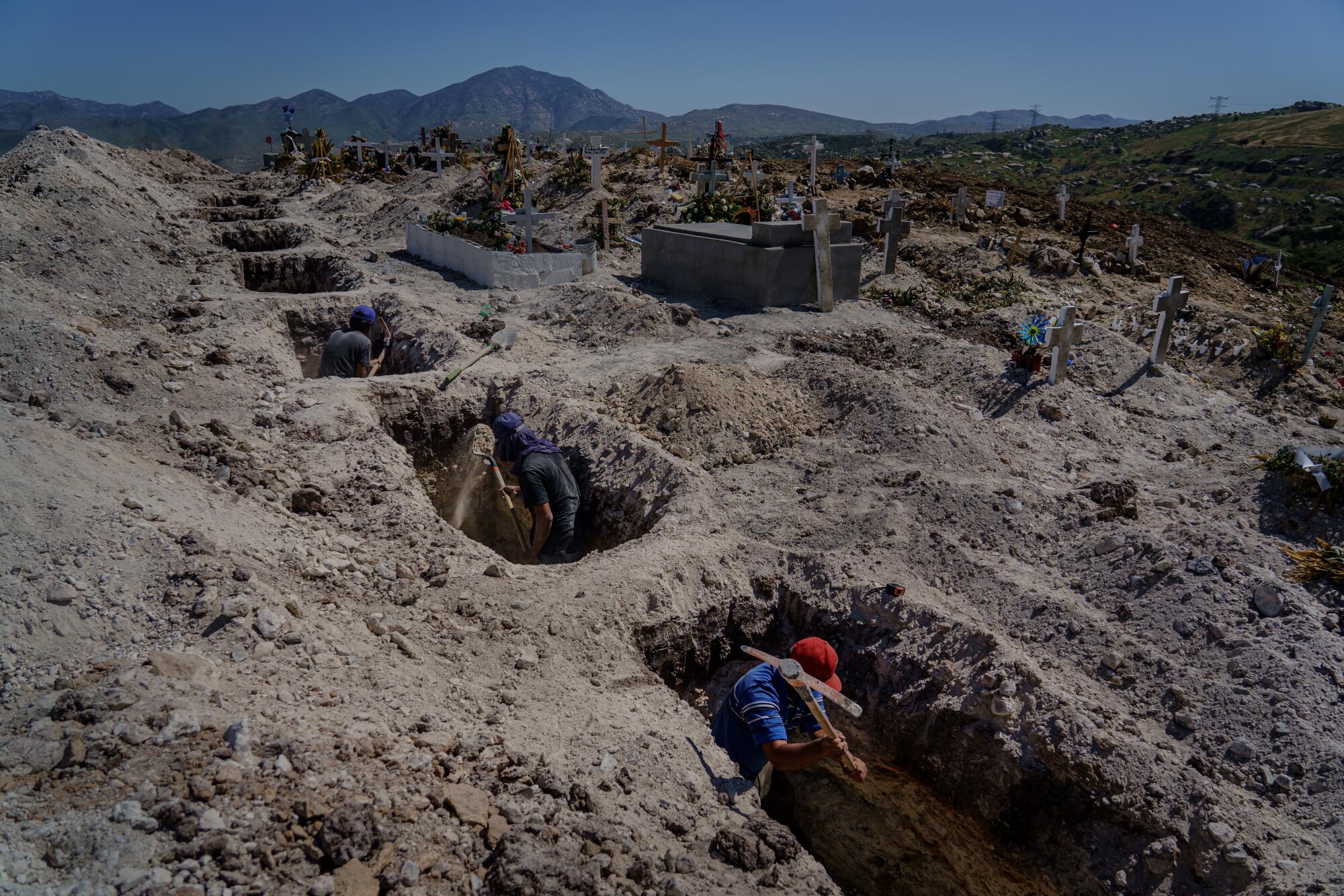 Cemetery workers dig holes ahead of time for a new crop of graves at the municipal pantheon number 13 cemetery, in Tijuana, Mexico, on April 27, 2020.