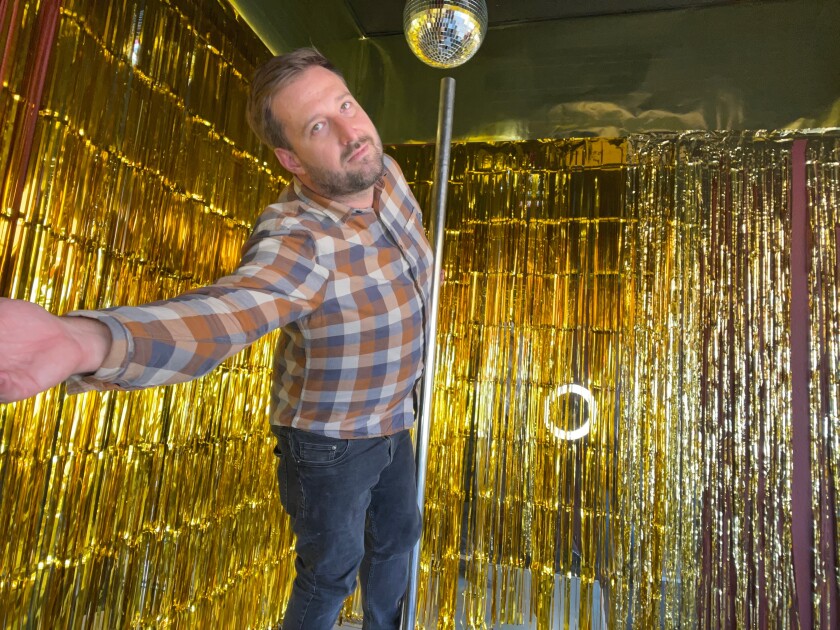 A man in a room with gold walls and a disco ball