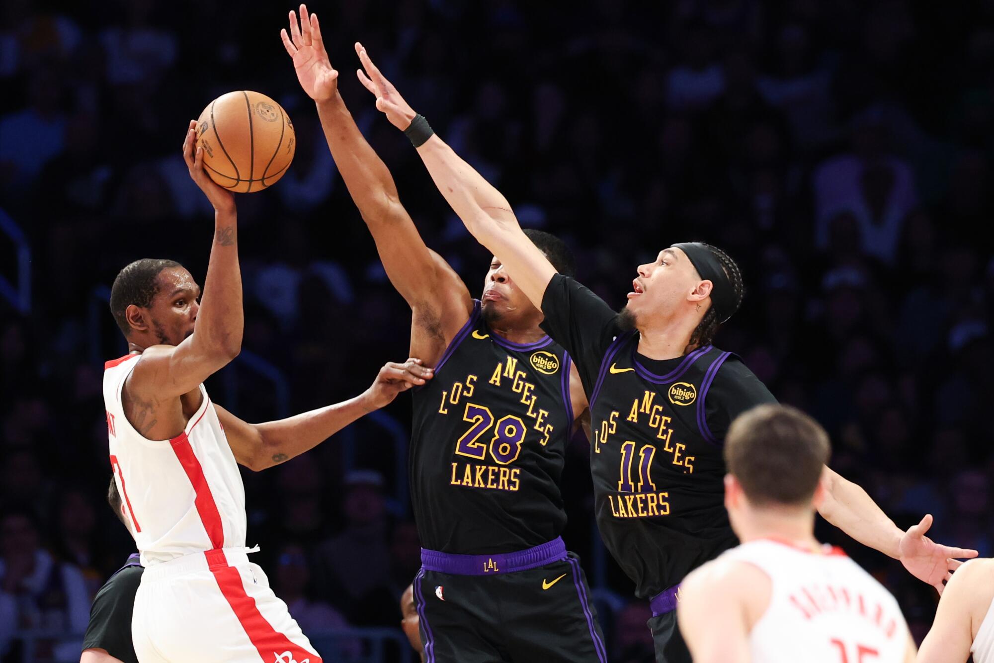 Houston forveti Kevin Durant, Lakers forveti Rui Hachimura ve pivot Jaxson Hayes'in baskısıyla topu paslıyor.