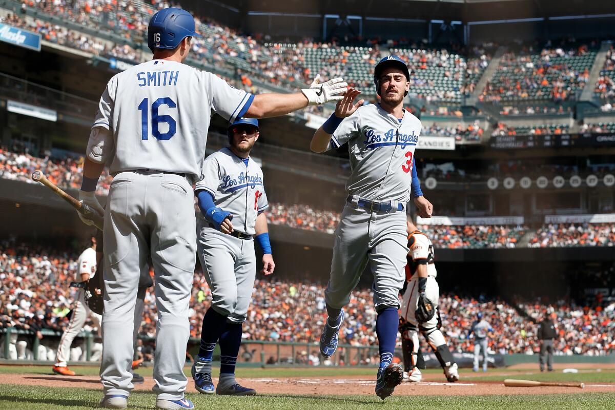 Dodgers teammates Cody Bellinger, right, and Max Muncy, center, celebrate.