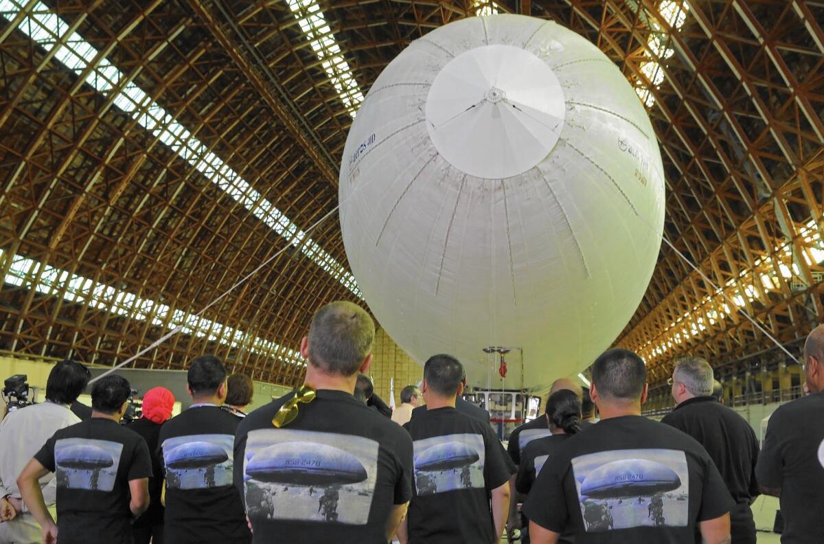 Employees of Worldwide Aeros Corp. watch the dedication of the Aeros 40D Sky Dragon airship in a World War II-era blimp hangar in Tustin.