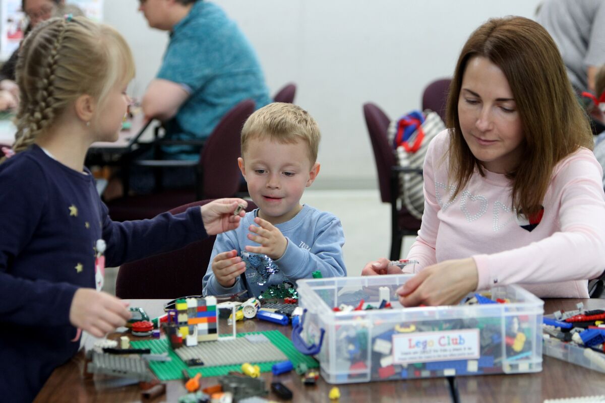 Natalia Kulikova (right) and her children Kseniia (left), 8, and Andrei, 3, play with LEGOs at a library's LEGO Club on March 7, 2020; before public libraries were closed due to coronavirus (COVID-19) concerns, Experts recommend parents have kids do stimulating, hands-on activities at home and have a daily routines during school closures.