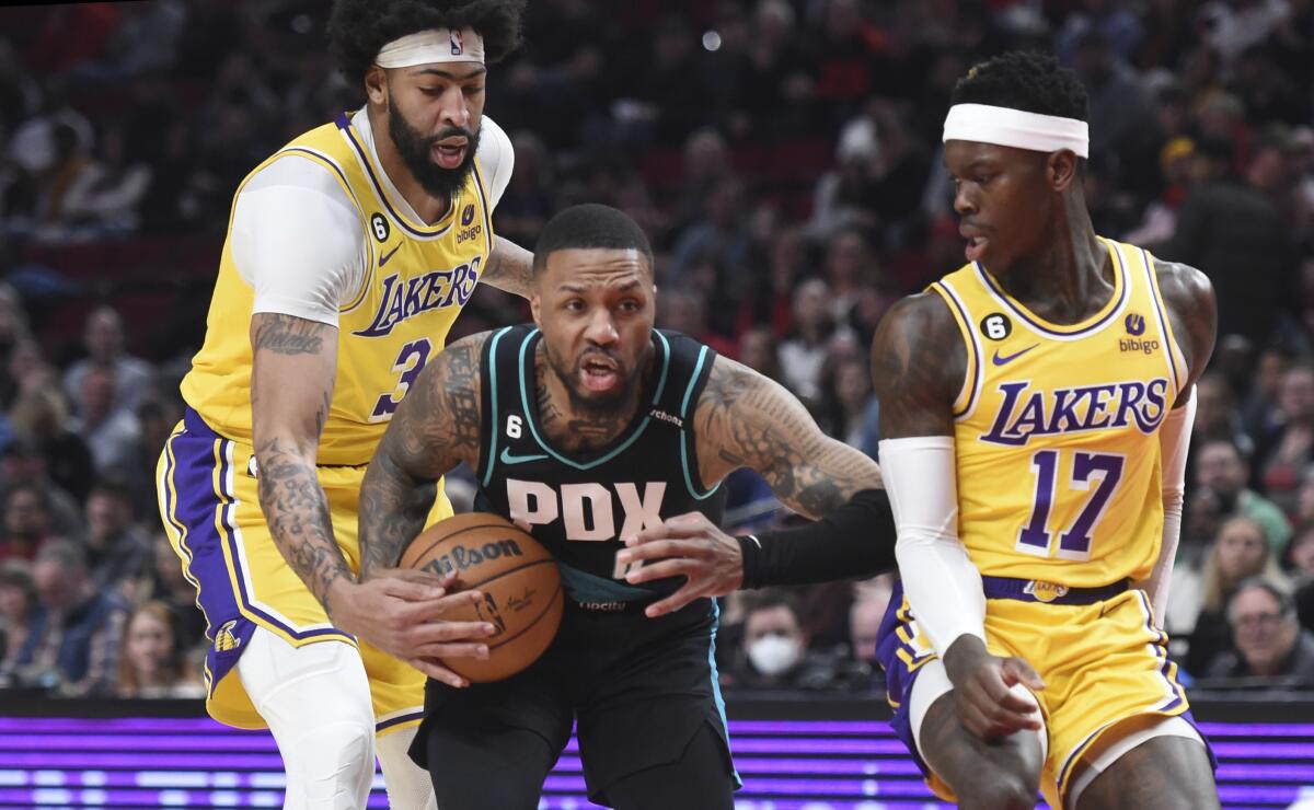 Portland Trail Blazers' Damian Lillard drives to the basket against Lakers' Anthony Davis and Dennis Schroder.