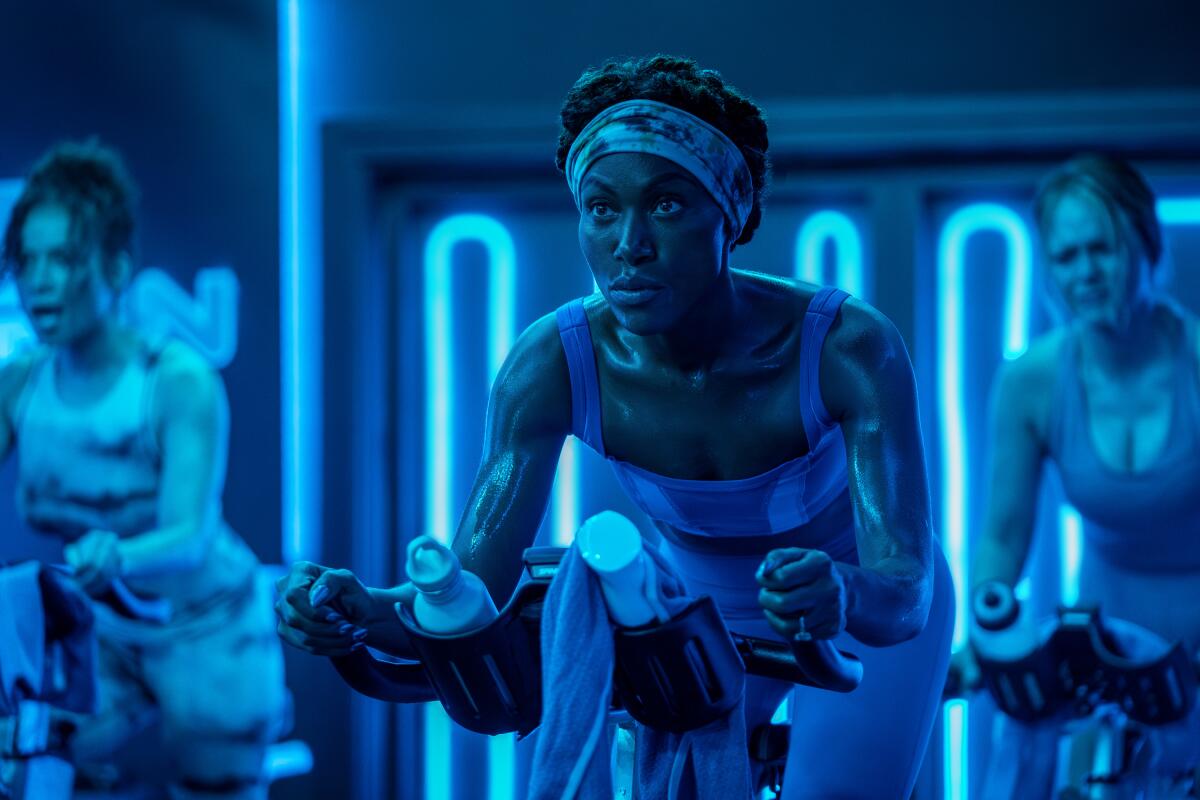 A woman in a cycling class bathed in deep blue light.