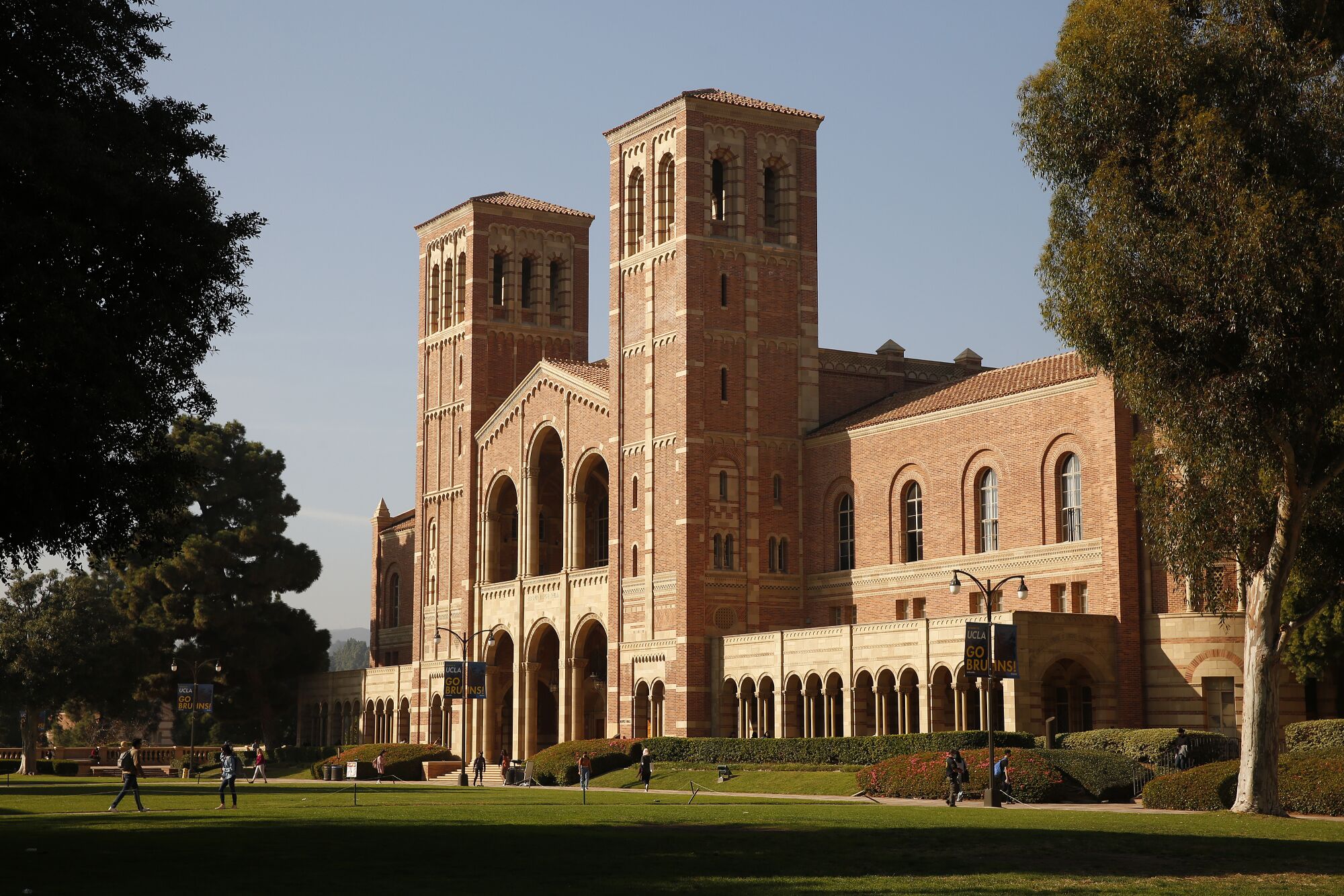 People walk around outside a large building on the campus of UCLA
