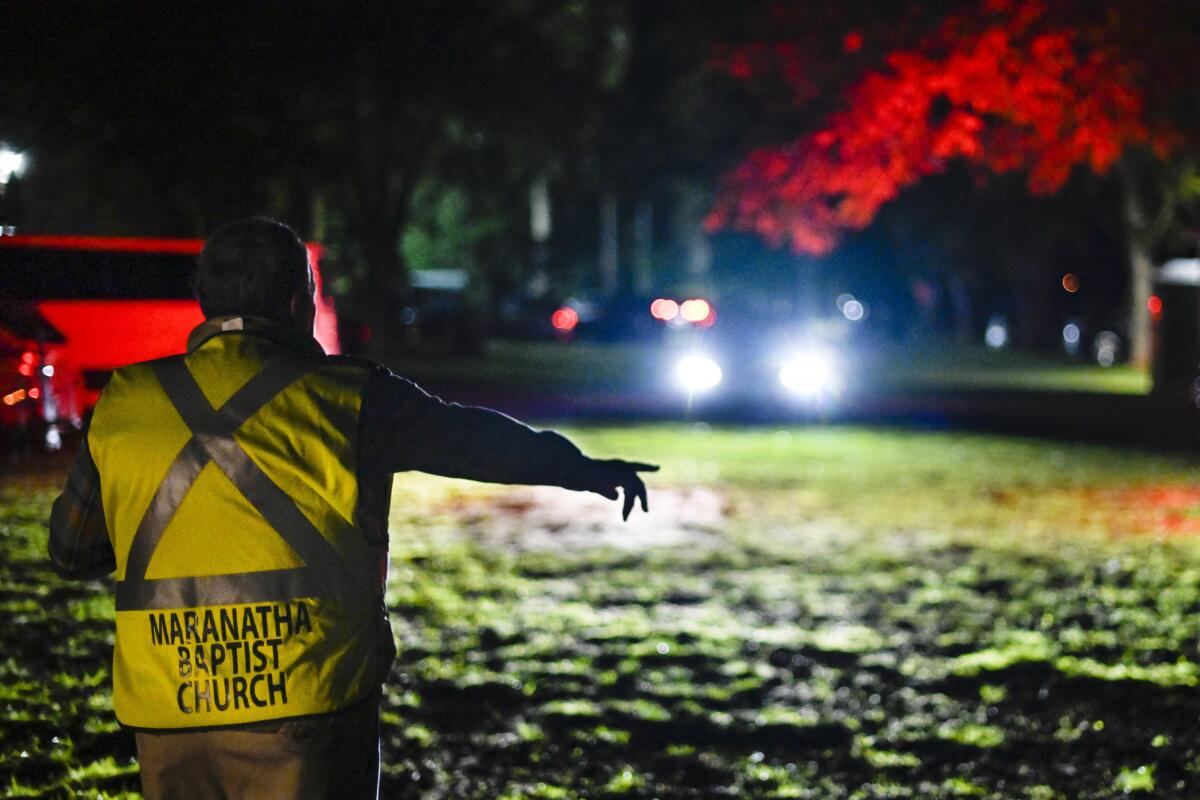 Mayor L.E. “Boze” Godwin III directs cars to parking behind Maranatha Baptist Church in Plains, Ga., before dawn.