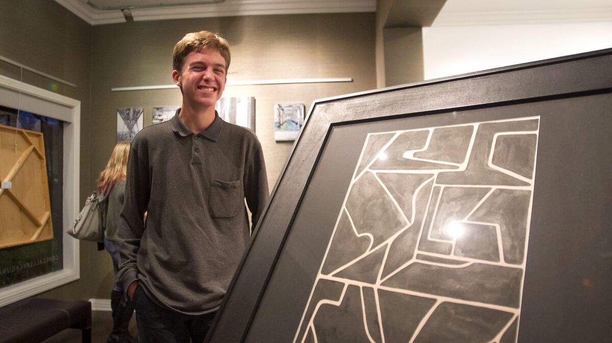 Laguna Beach High student Zander Raymond stands next to his ink on paper piece “Shape Study” at the Cove Gallery during Thursday's Art Walk. The gallery and high school partnered on a program that allows two artists at a time to display their work.