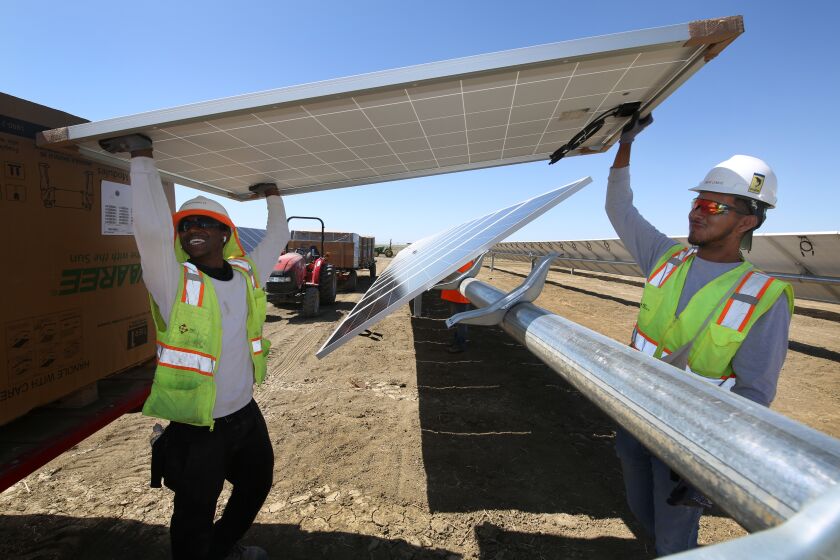 LEMOORE CA JUNE 24, 2021 - From left to right, Rayshawn Lee and Omar Lemus place panels at the construction site of Westlands Solar Park, which when completed will be one of the largest solar farms in the nation located in Lemoore, Calif., Thursday, June 24, 2021. (Gary Kazanjian/For The Times)